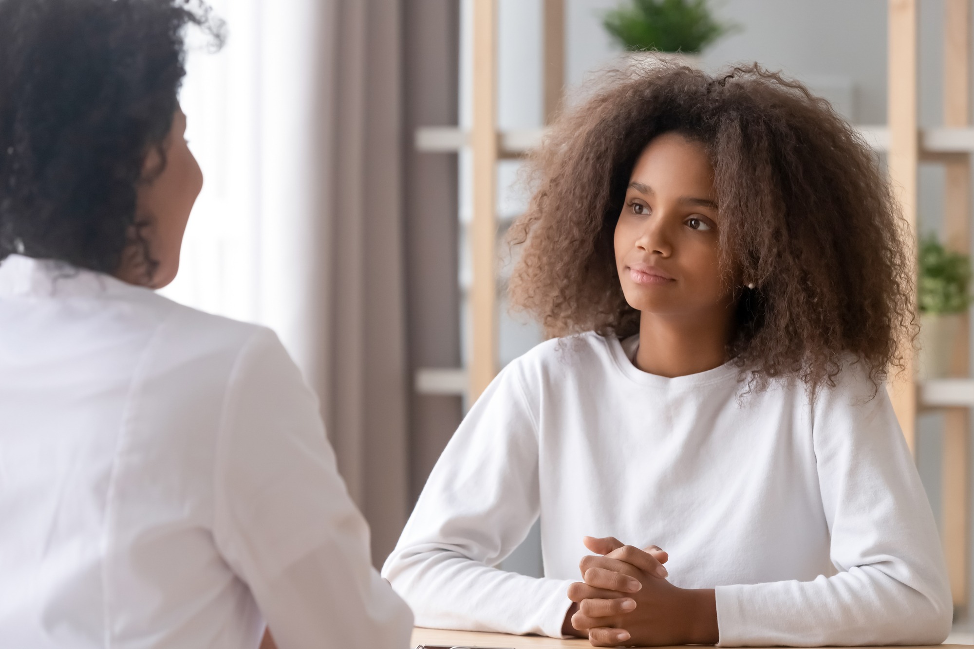 Focus on african adolescent teen girl listening medical worker her psychotherapist