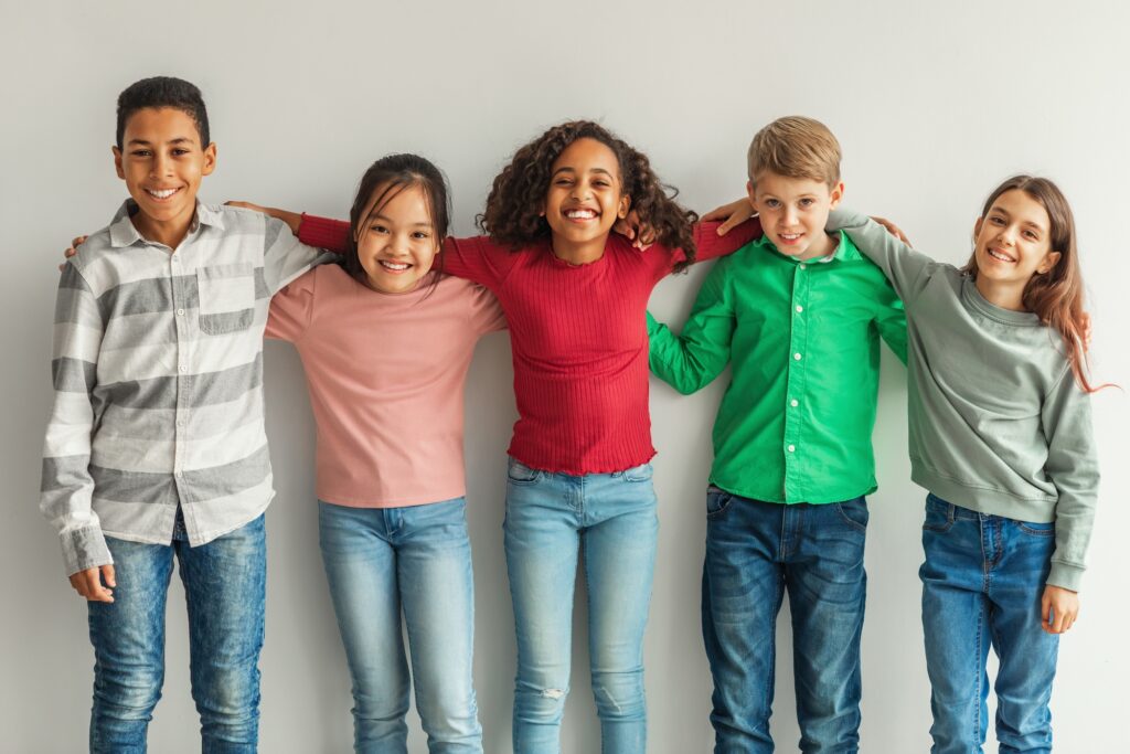 Cheerful Multiethnic Children Hugging Posing Smiling To Camera Indoor
